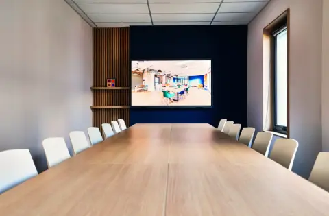 Salle de réunion avec grande table et un écran connecté et interactif