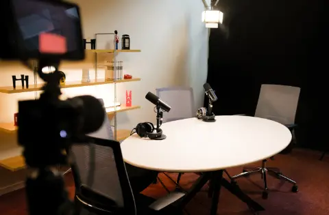 Studio d'enregistrement podcast avec micros, caméras, table et chaises