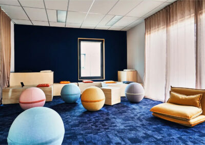 Salle Créa Inès avec coussins au sol, assises modulables, ballons colorés et décor mural artistique, conçue pour stimuler la créativité.