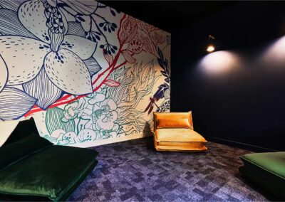 Salle de sieste équipée de coussins au sol, ballons d’assise colorés et banquettes en bois, dans une ambiance douce et reposante.