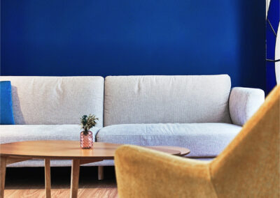 Salon cosy de La Passerelle Coworking avec canapé gris clair, fauteuil jaune design et table basse en bois, dans une ambiance moderne et chaleureuse.