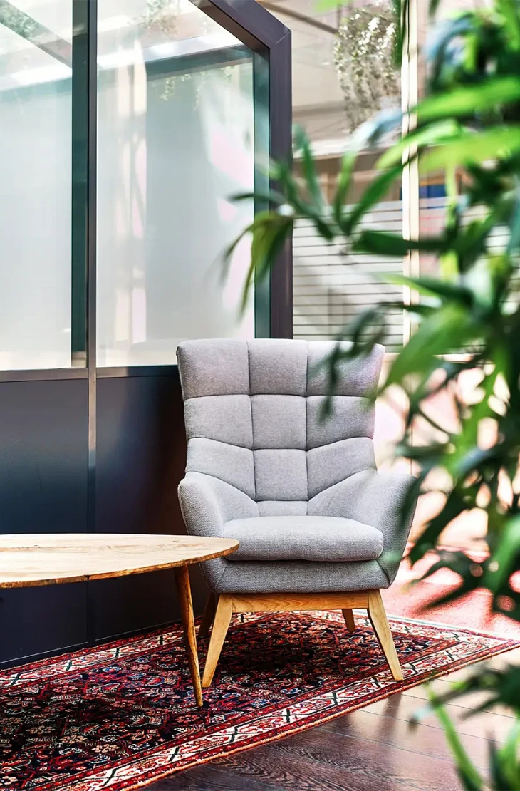 Aperçu du passage au milieu des bureaux, avec un fauteuil confortable, une jolie table basse et un tapis chaleureux