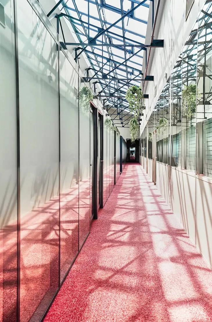 04-vue-interieure-bureau-passerelle-730x1110 Vue du grand salon dans la longueur, avec l'aperçu de plusieurs espaces : petits salons, table pour travailler, phone box. Un espace lumineux et ouvert sur patio et jardin